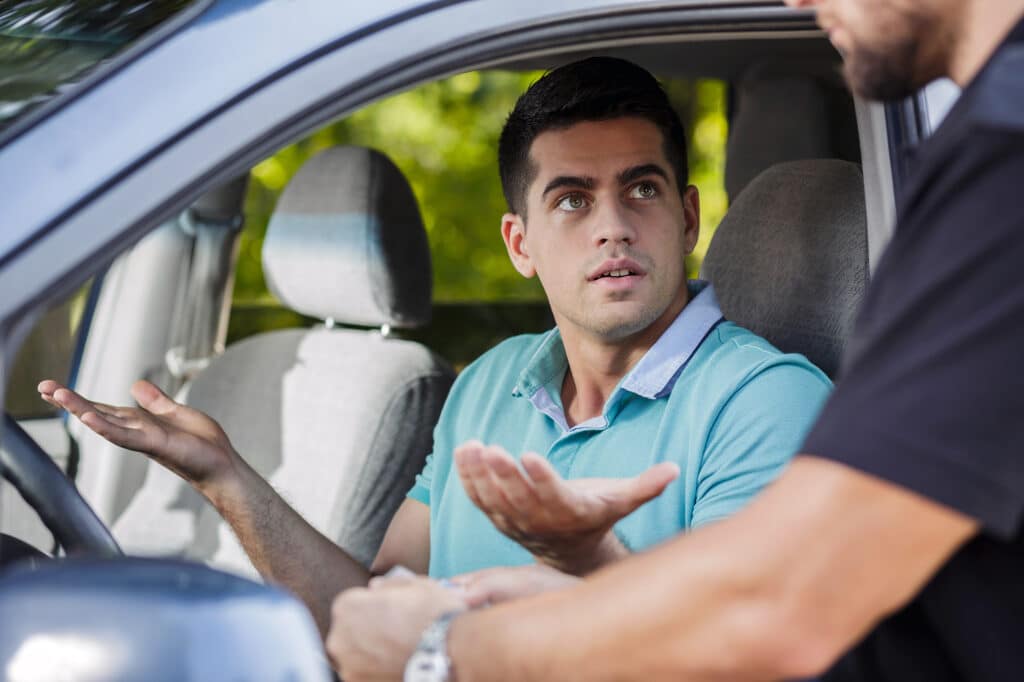 Confused young man in the car stopped by policeman for a traffic stop