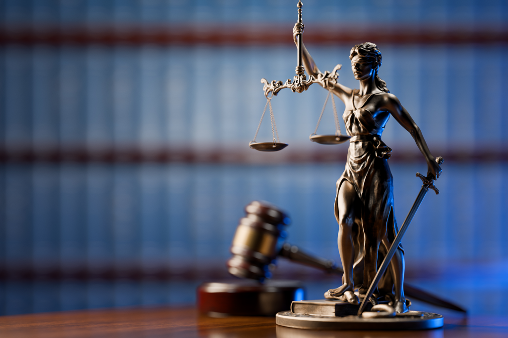 Lady of Justice statue with gavel and law books in background