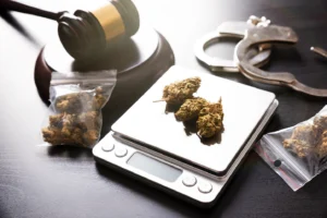 Marijuana on a scale next to plastic bags, handcuffs, and gavel